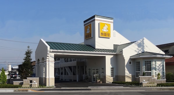 A building with a green roof, a central entrance, and a sign with a cartoon character. - Family Lodge Hatagoya Sanuki Kanonji (Kanonji)