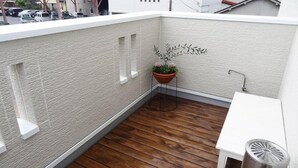 A small balcony with a wooden floor, a white wall, and a potted plant. - Family Lodge Hatagoya Sakaiminato (Sakaiminato)