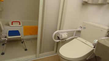 A bathroom with a white toilet, a blue seat, a white grab bar, and a yellow towel.