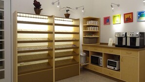 A room with a wooden shelving unit with multiple compartments, a microwave, a toaster, and a small trash bin. There are wall-mounted lights and a few framed pictures on the wall. - Family Lodge Hatagoya Izumo Taisha (Izumo)