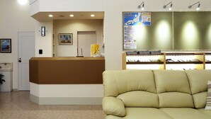 A reception area with a beige sofa, a reception desk, a clock, and a map on the wall. - Family Lodge Hatagoya Izumo Taisha (Izumo)