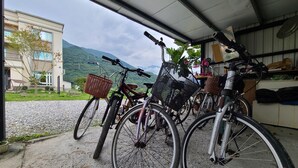 Bicycles parked inside a garage with a view of a building and mountains in the background. - Flower 280 (Ji'an)