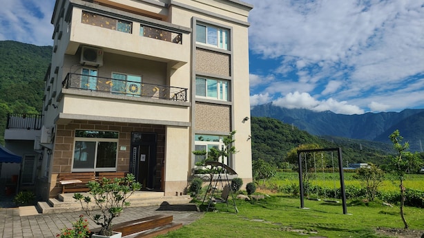 A multi-story building with a balcony, a small garden area with steps leading to the entrance, and a mountainous backdrop. - Flower 280 (Ji'an)
