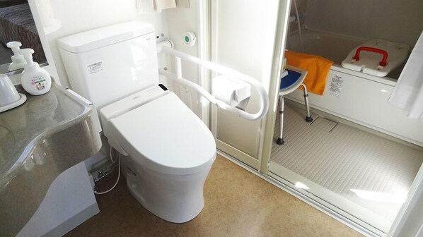 A modern bathroom with a toilet, a handrail, a shower chair, and a sink. - Family Lodge Hatagoya Shimizu Okitsu (Shizuoka)