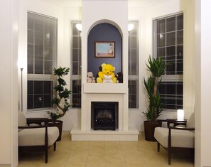 A living room with a fireplace, two armchairs, a sofa, and a large window with blinds. - Family Lodge Hatagoya Shimizu Okitsu (Shizuoka)