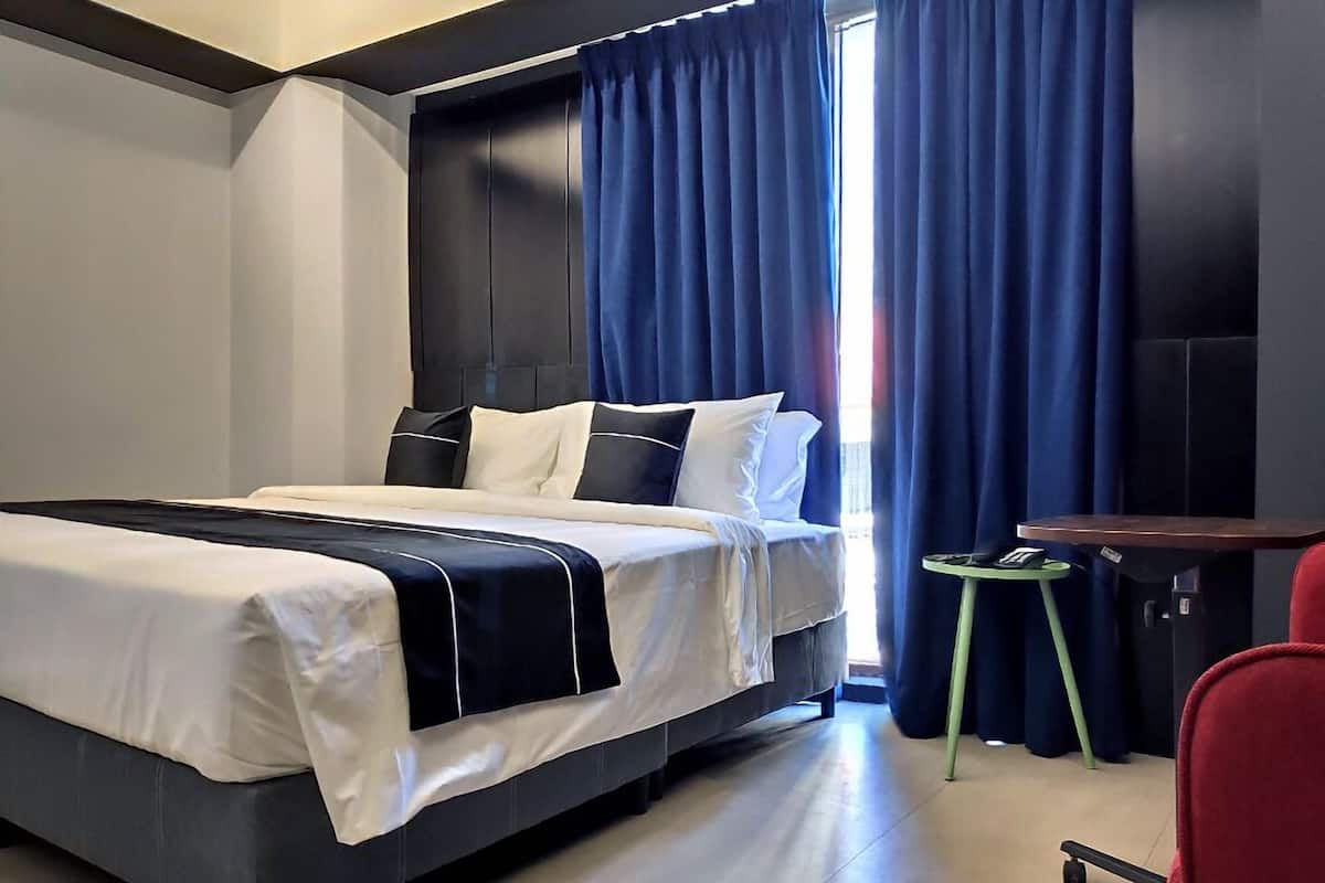 Ein modernes Hotelzimmer mit einem großen Bett, einem kleinen Schreibtisch und einem Stuhl.