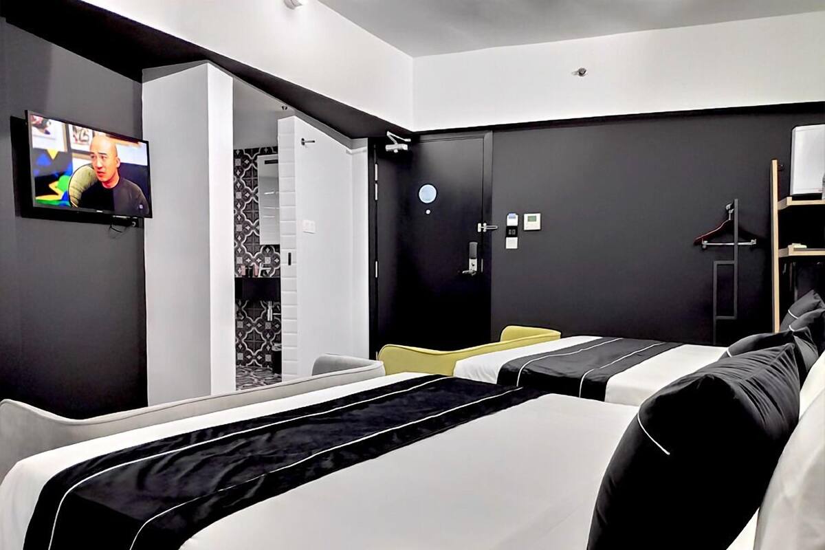 Ein modernes Hotelzimmer mit Bett, Fernseher, Badezimmer und Kleiderhaken.