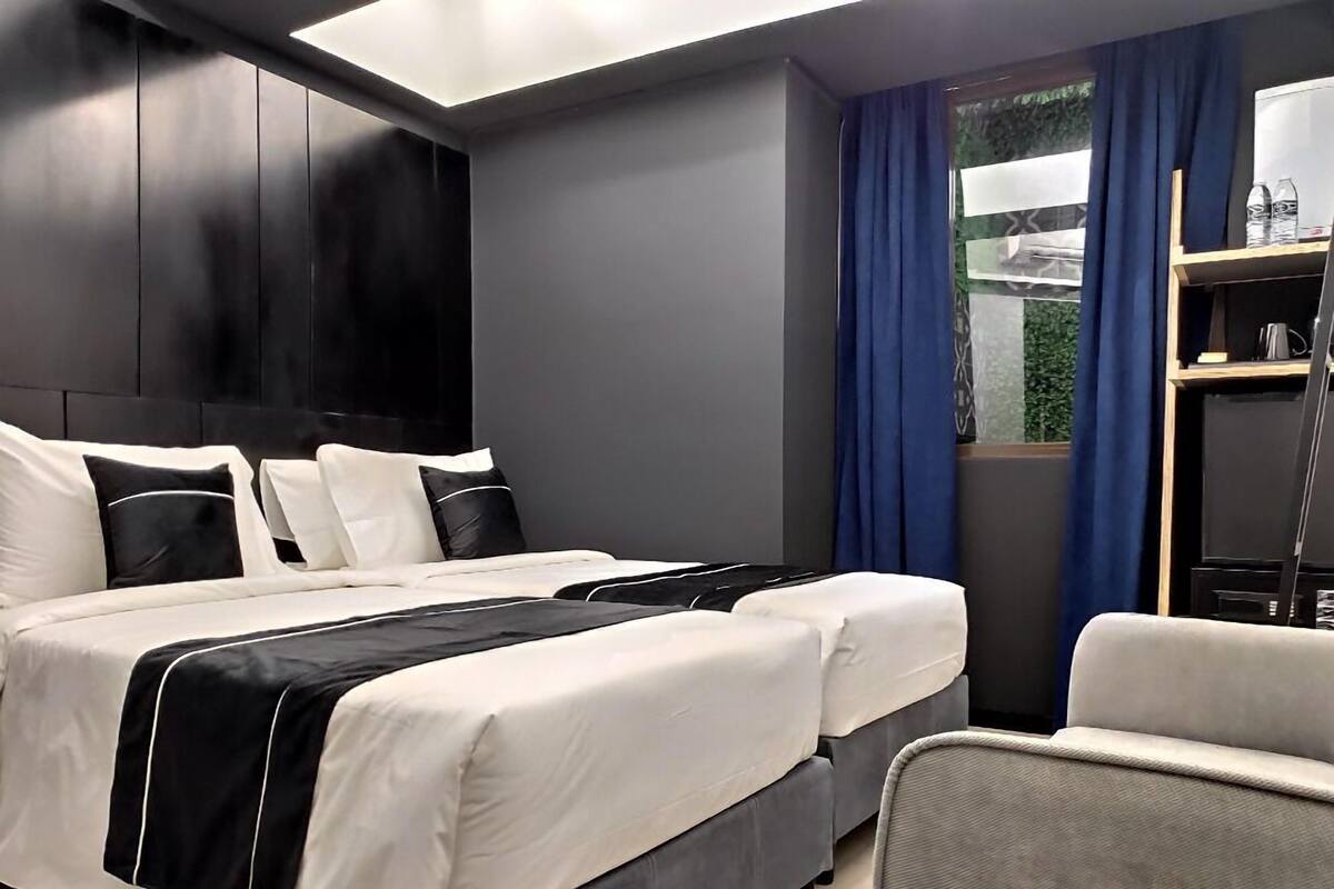 Ein modernes Schlafzimmer mit einem großen Bett, zwei Nachttischen, einem Sessel und einem Kleiderschrank.