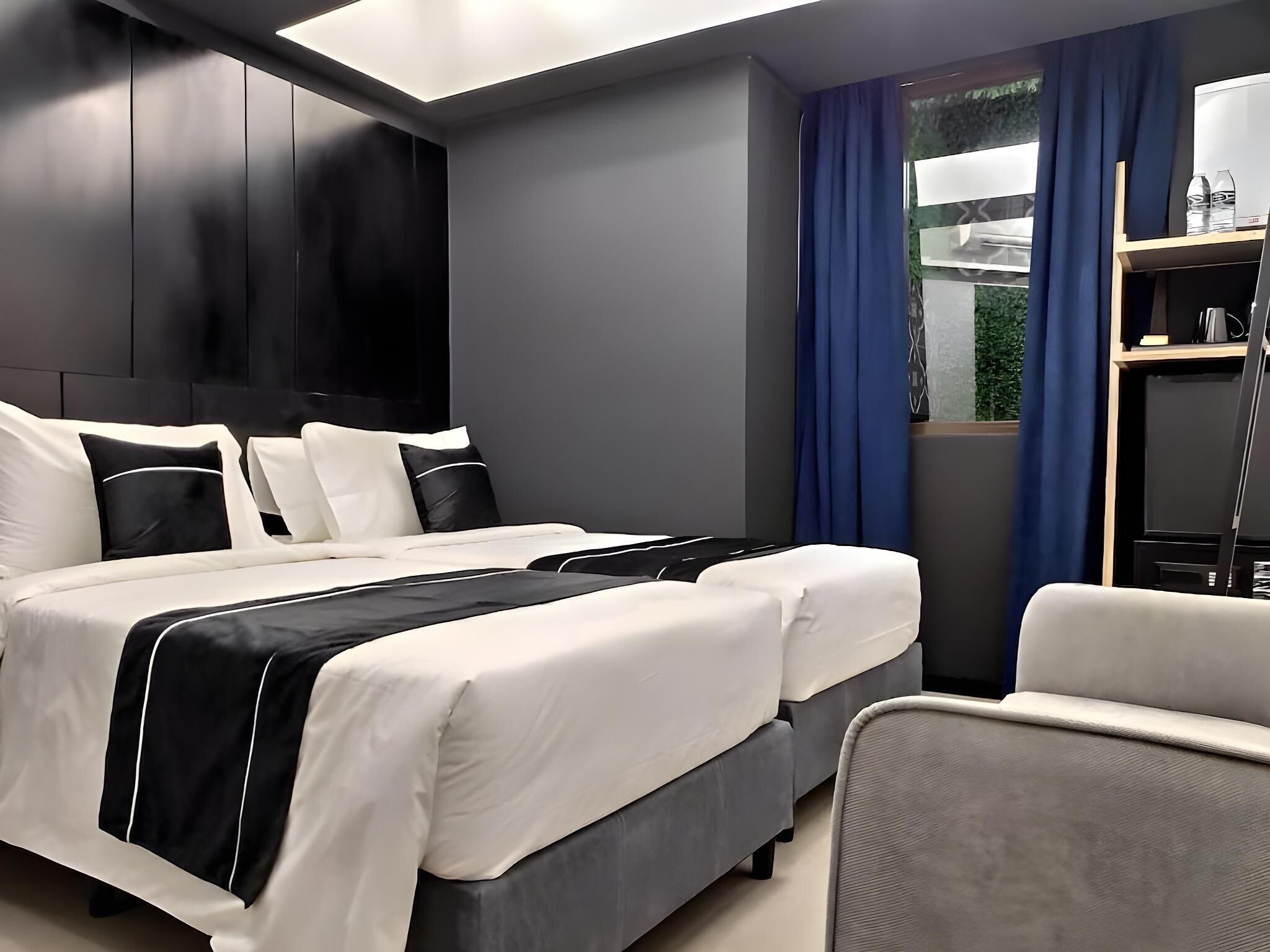 A modern hotel room with a large bed, a desk, and a chair.