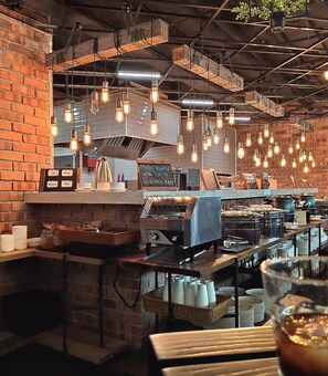 A restaurant interior with exposed brick walls, hanging light bulbs, and a coffee machine. - Loop On Leith Hotel Penang (George Town)