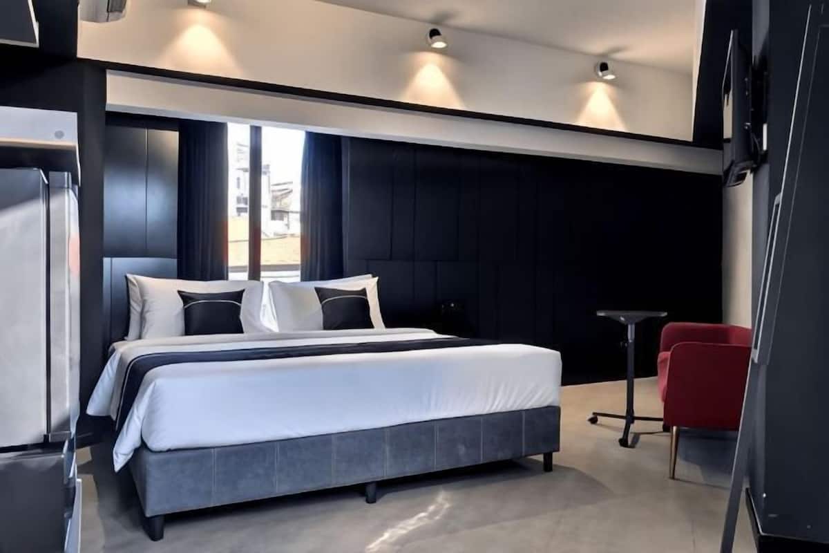 A modern hotel room with a large bed, a small desk, and a red chair.