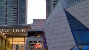 Un edificio moderno con un llamativo letrero que dice 'PAVILION', que presenta una fachada geométrica y el logotipo de Superman al fondo.