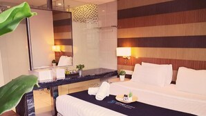 Una habitación de hotel con una cama grande, un escritorio con espejo y una mesita de noche con artículos de aseo.