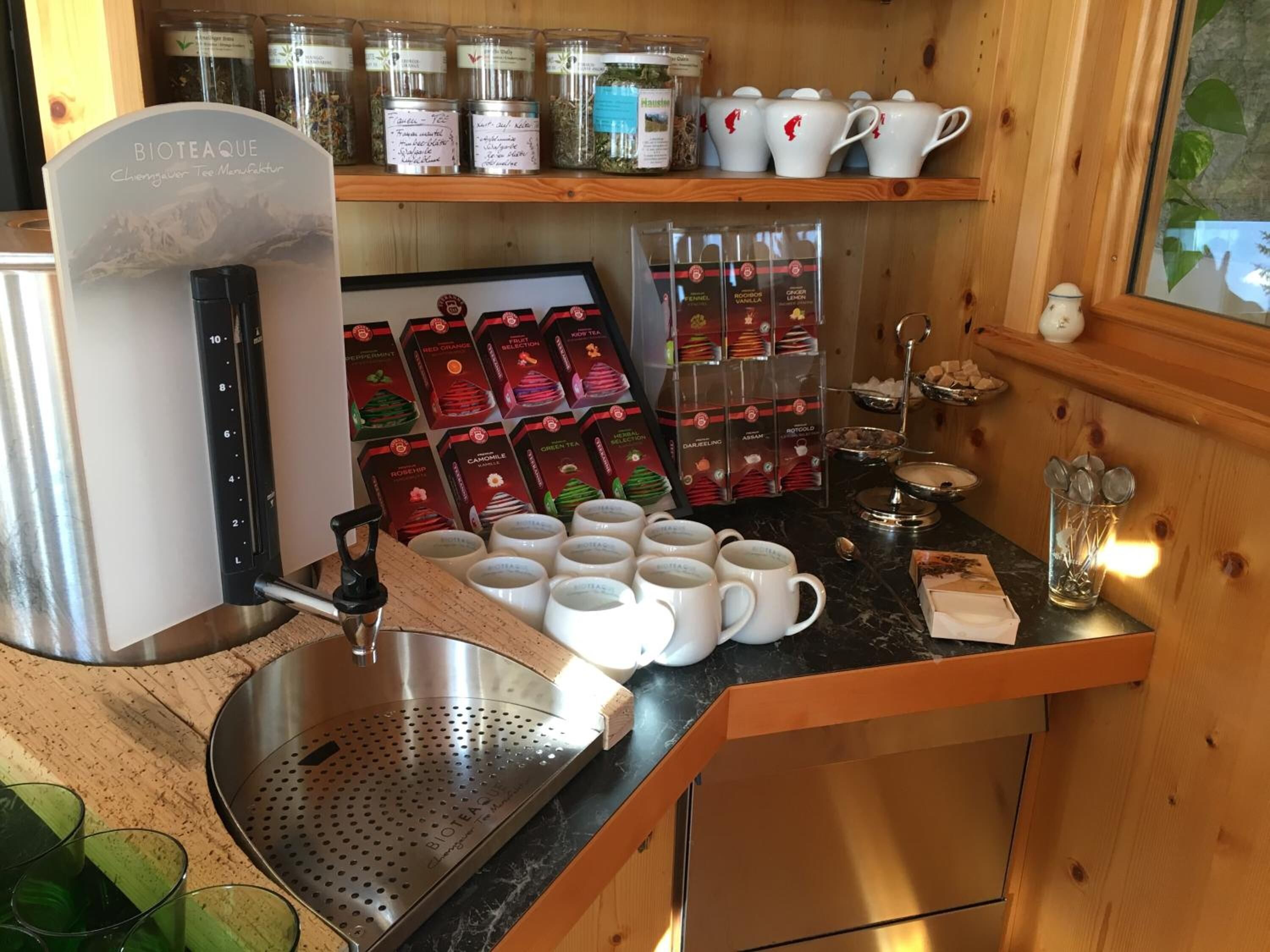 A kitchenette with a coffee machine, tea dispensers, and a variety of tea boxes.
