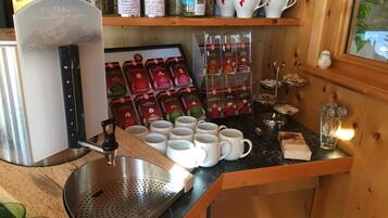 A kitchenette with a coffee machine, tea dispensers, and a variety of tea boxes.