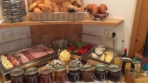Un bufé con distintos alimentos, incluyendo carnes, quesos y pasteles.