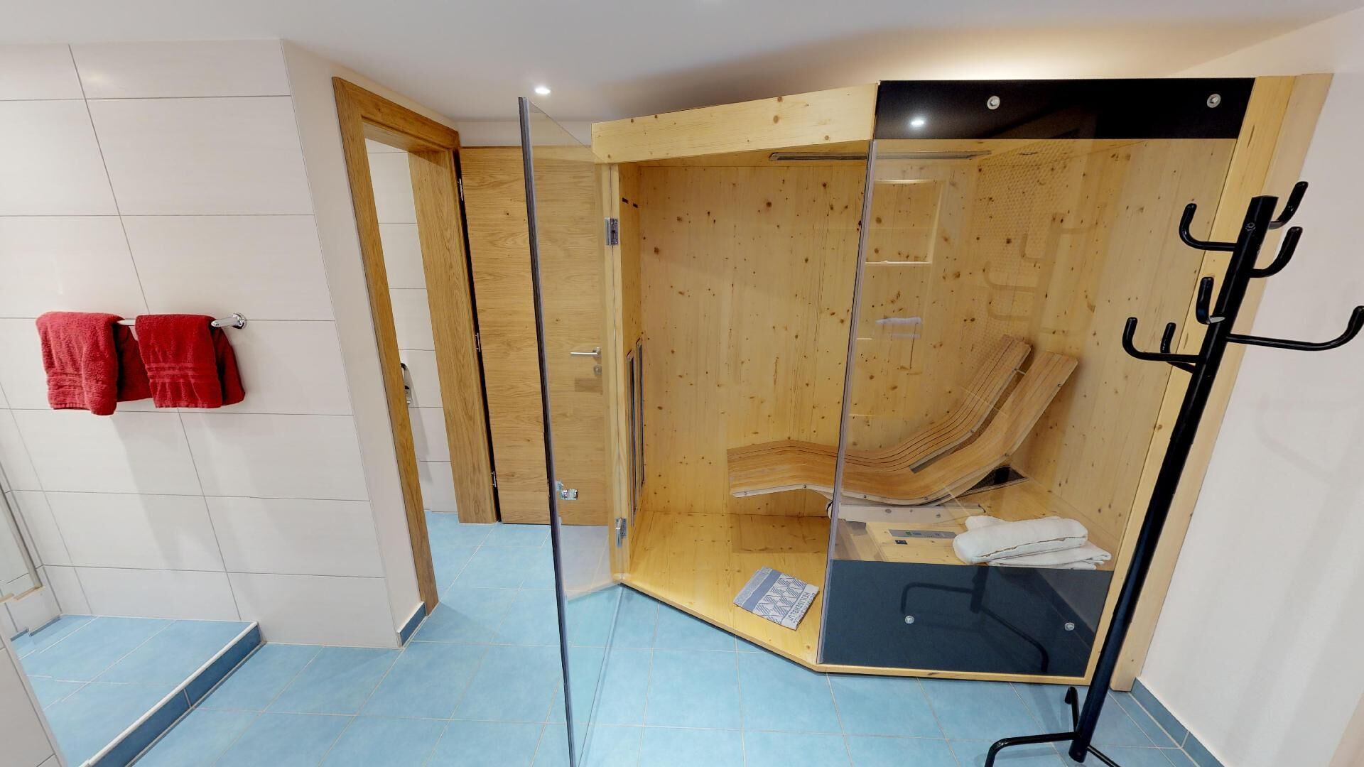 Una habitación con un separador de madera, un perchero negro y una toalla roja en un esqueleto.