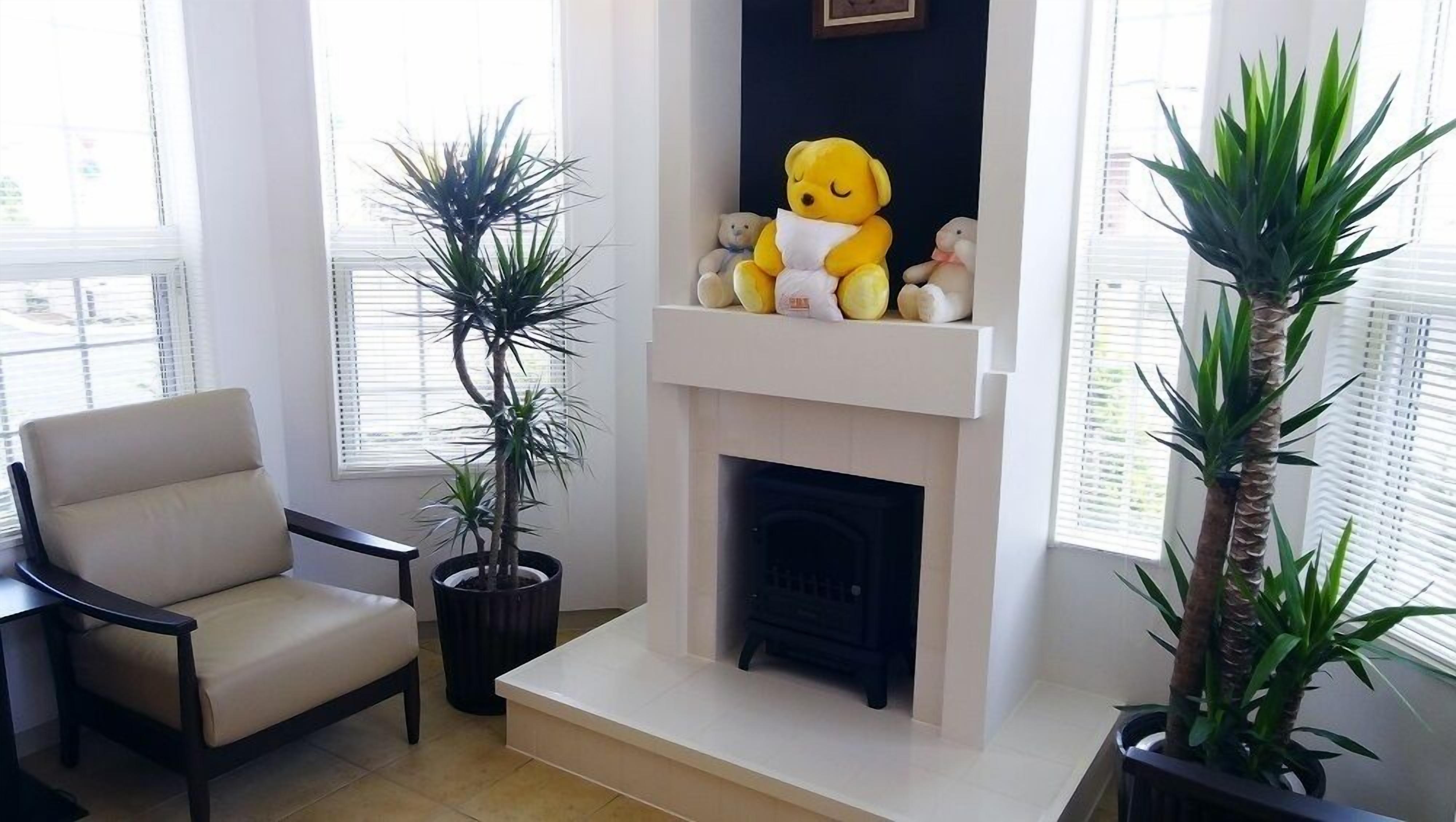Una sala de estar con un sofá color beige, una chimenea y dos plantas en macetas.