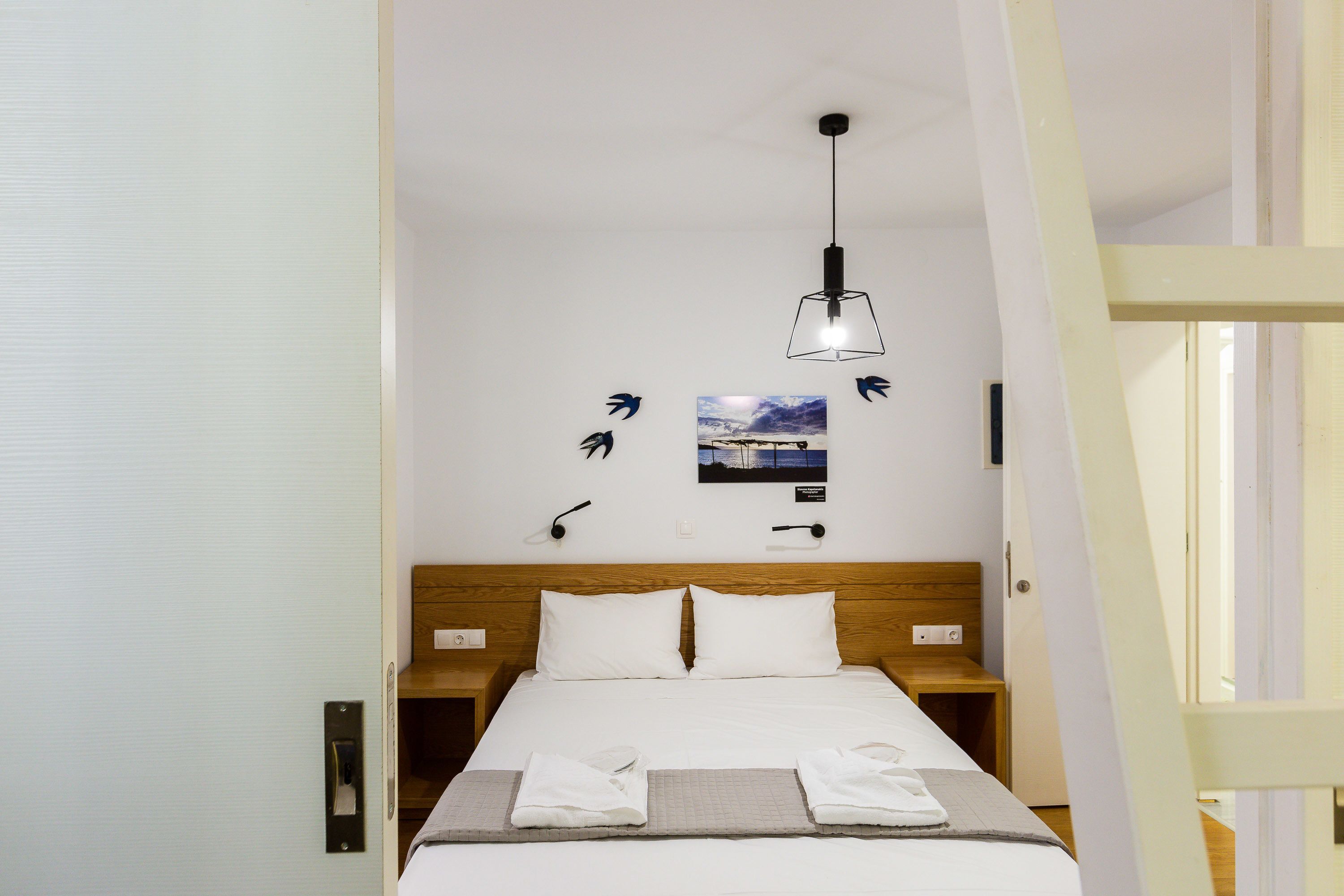 A neatly made bed with white linens, a wooden headboard, and a bedside table with a lamp.