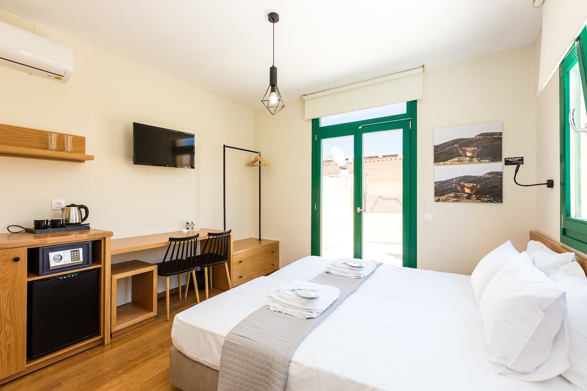 A hotel room with a bed, a desk, a chair, a TV, and a small fridge.