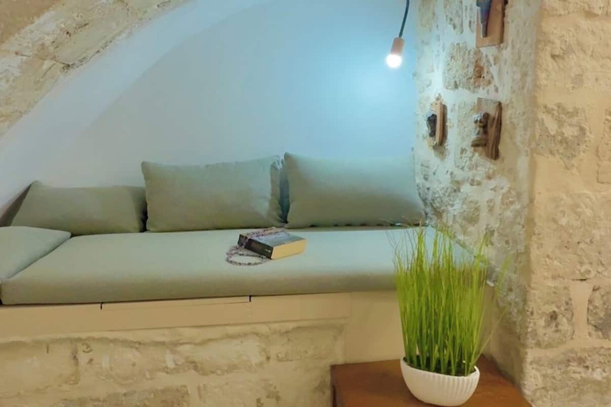 A cozy room with a stone wall, a wooden bench, and a green plant.