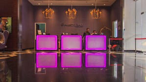 Ein Hotel-Empfangsbereich mit einer Rezeption, einem großen Spiegel und einer Kristallleuchtre.