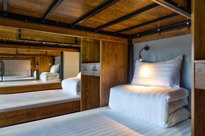 A hotel room with a wooden ceiling, a bed with white bedding, a bedside table, and a mirror reflecting the room. - Lustig Hostel (Sa Pa)