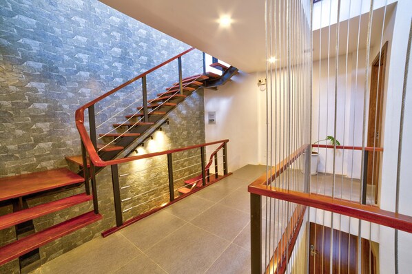 A modern staircase with a stone wall backdrop, metal railings, and a view of the upper floor. - Lustig Hostel (Sa Pa)