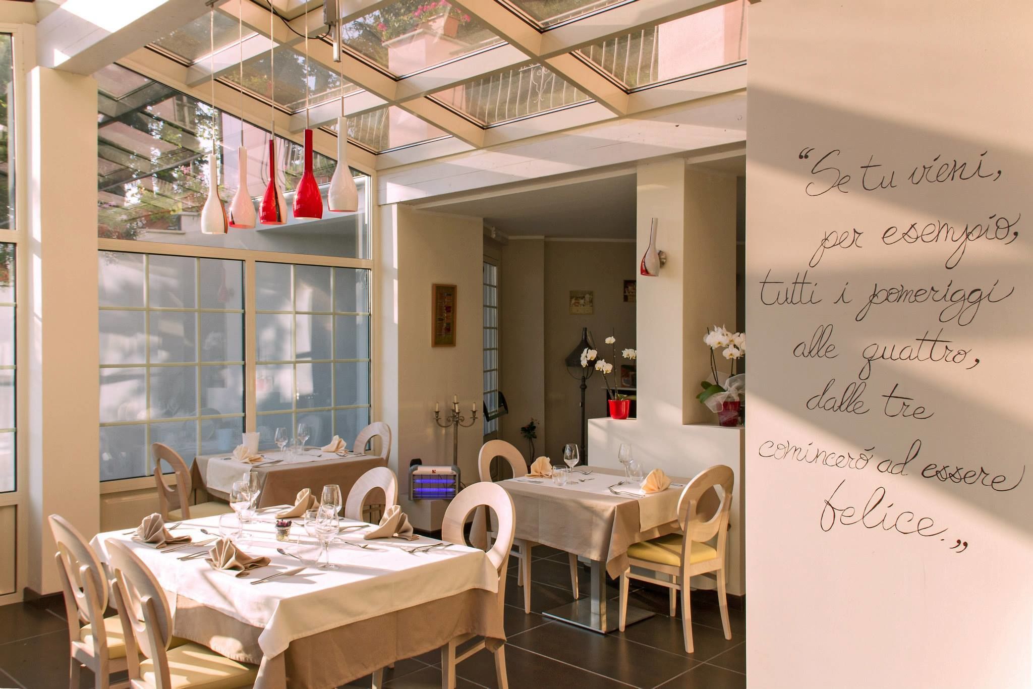 Un comedor con mesas dispuestas para cuatro, un ventanal con vistas y una cita en la pared.