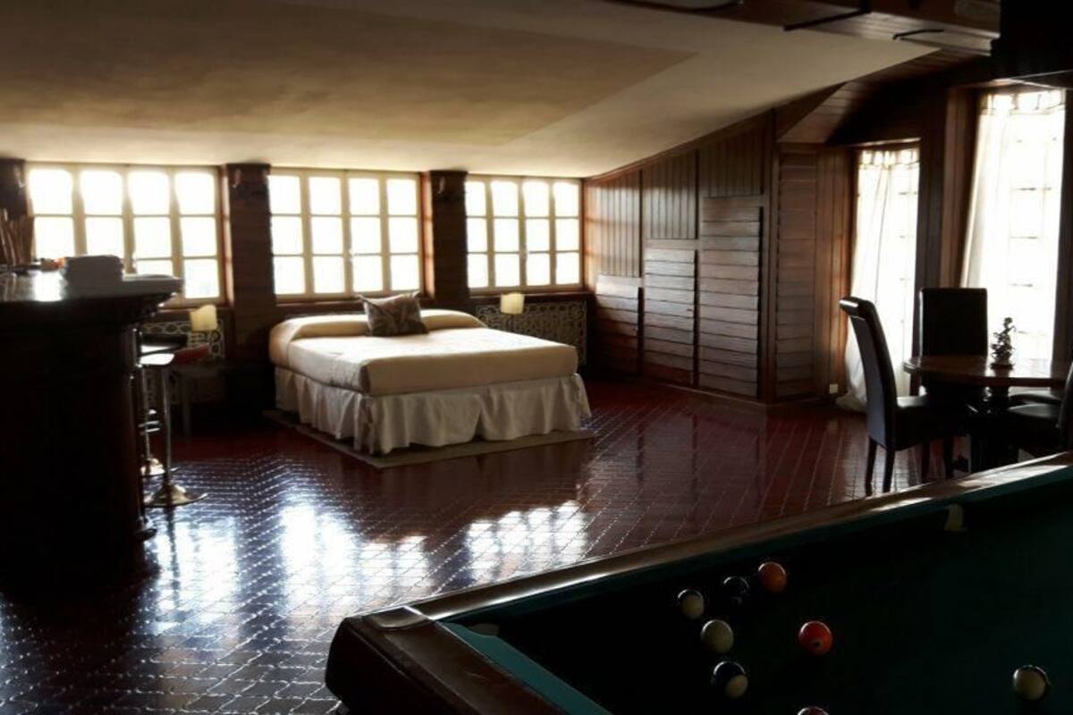 Una habitación con mesa de billar, cama y un amplio ventanal.