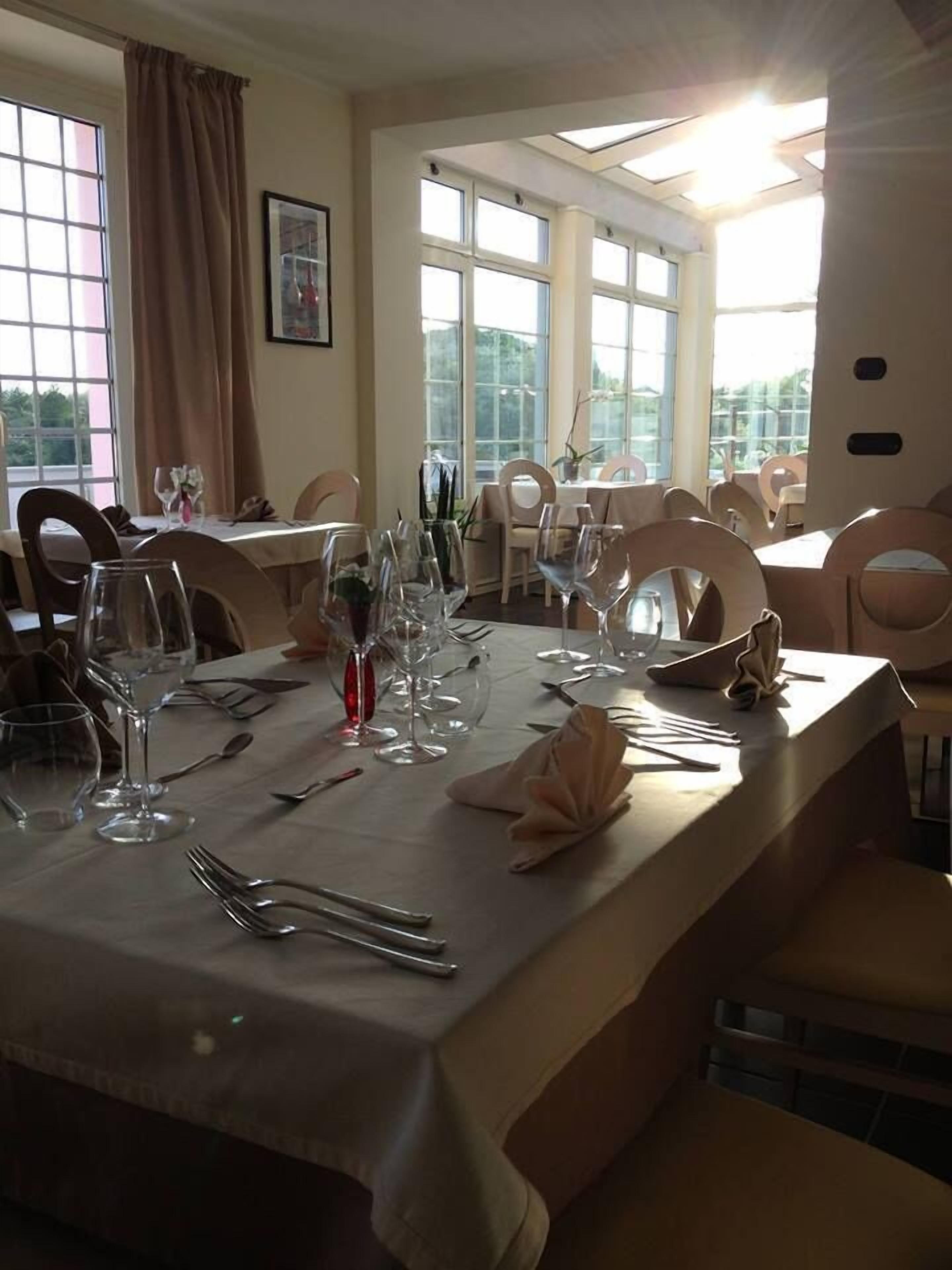 A dining table set for a meal with multiple chairs, a window with curtains, and a skylight.