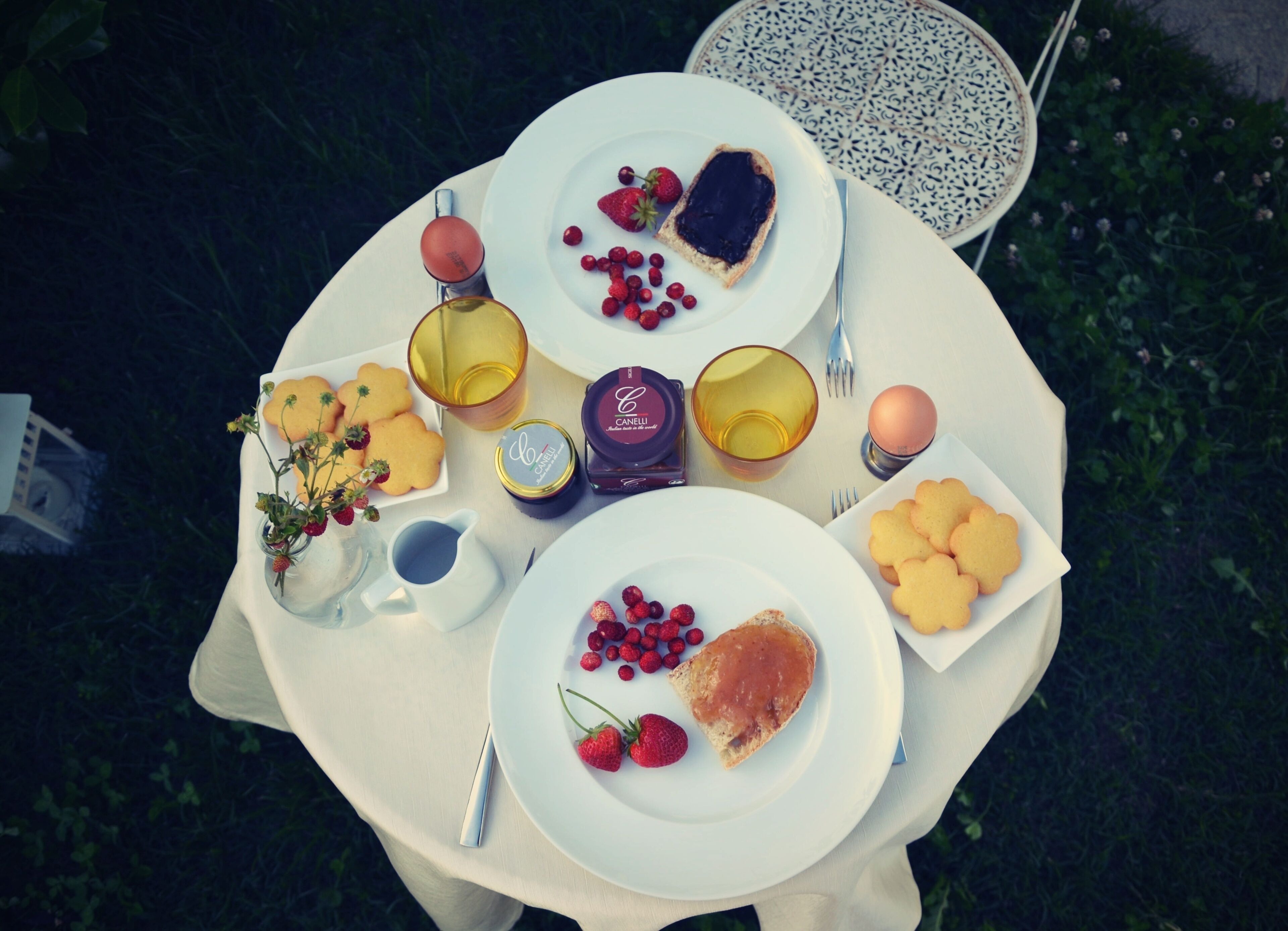 A round table with plates of food, a candle, and a glass of water.