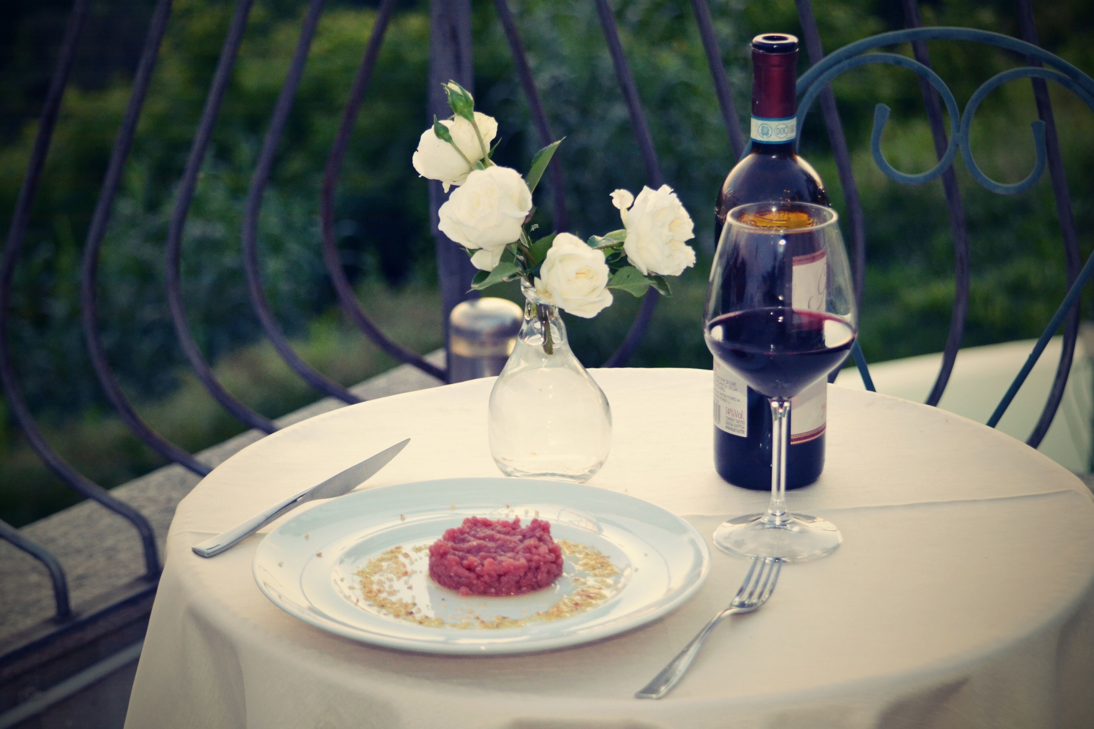 A table with a plate of food, a wine bottle, and a glass of wine.