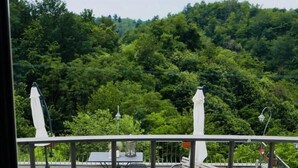 Ein Balkon mit Sitzgelegenheit im Freien, umgeben von üppiger Vegetation und einer Bergkulisse.