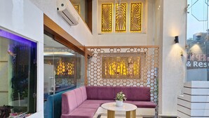 Um hall moderno com um sofá roxo, uma mesa redonda e painéis decorativos.