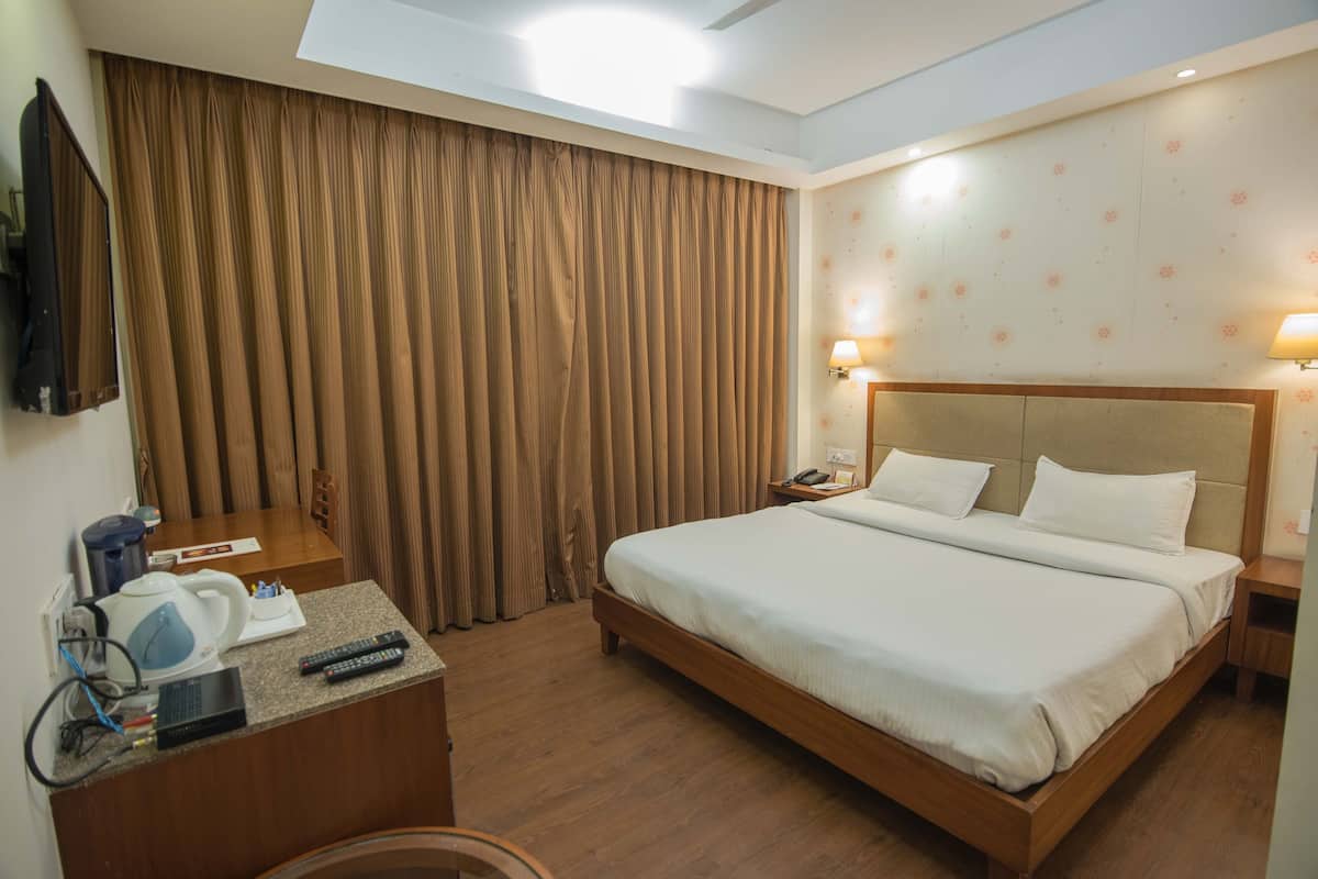 Quarto de hotel com uma cama grande, uma escrivaninha com chaleira, máquina de café e televisão.