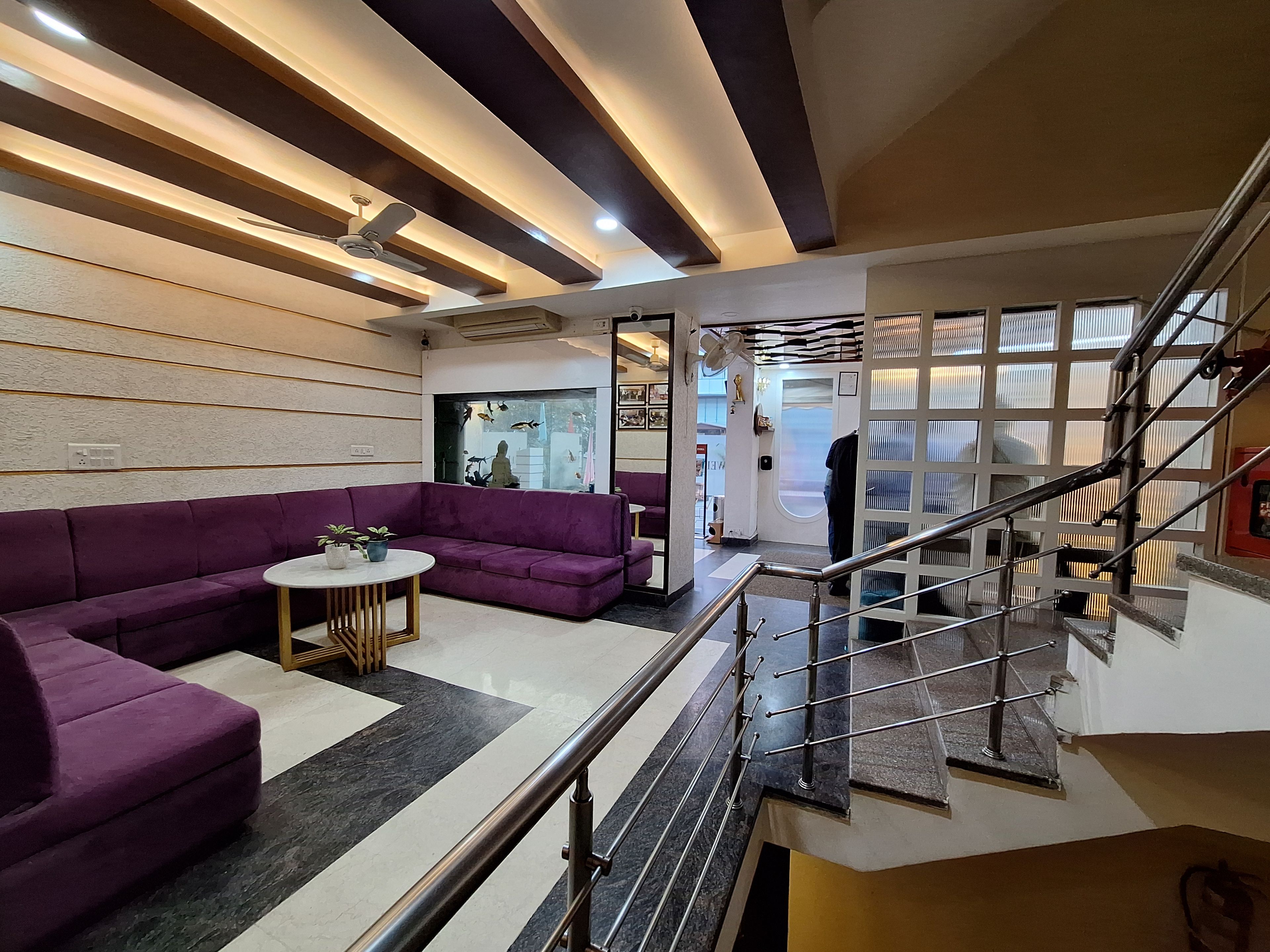 A modern interior with a purple sofa, a small round table, and a staircase with metal railings.