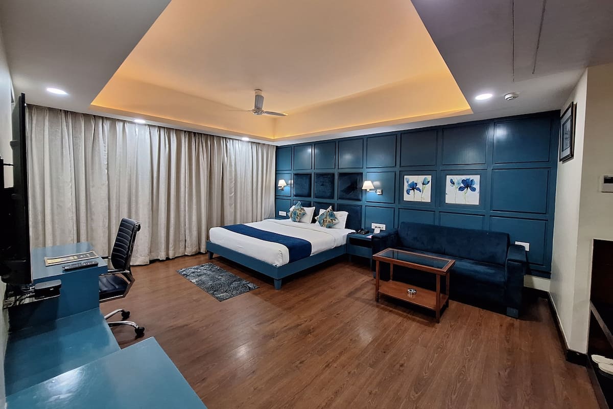 Quarto de hotel moderno com cama, escrivaninha, sofá e ventoinha no teto.
