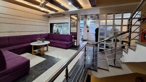 Um interior moderno com um sofá roxo, uma mesa redonda pequena e uma escadaria com grades de metal.