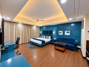 A modern hotel room with a bed, a desk, a sofa, and a ceiling fan. - L N Hotels and Resorts (Bhopal)