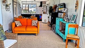 Una sala de estar acogedora con un sofá naranja brillante, un mueble azul turquesa y un sillón de mimbre.