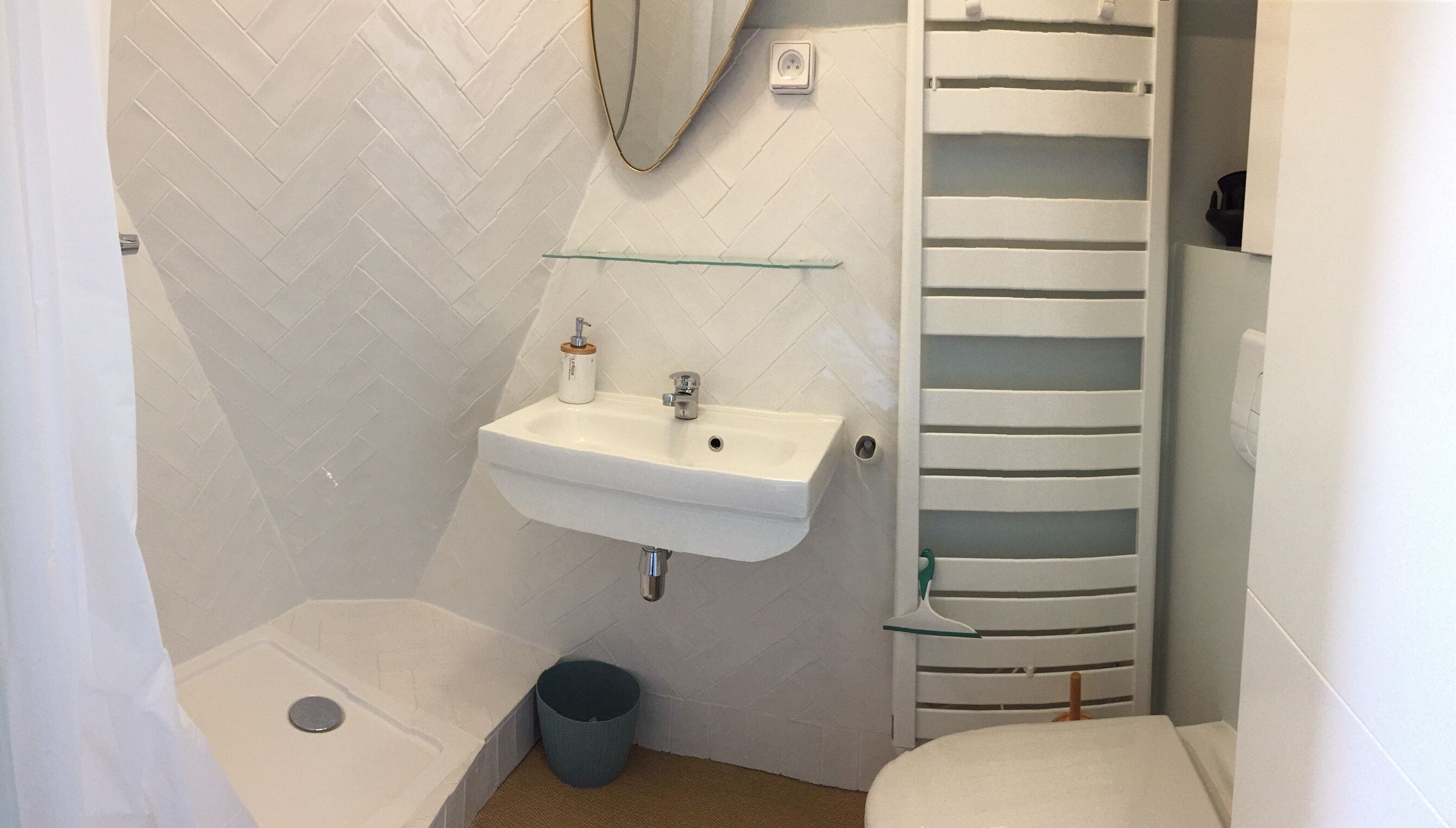 Une petite salle de bain avec un lavabo blanc, un miroir, des toilettes et une douche.