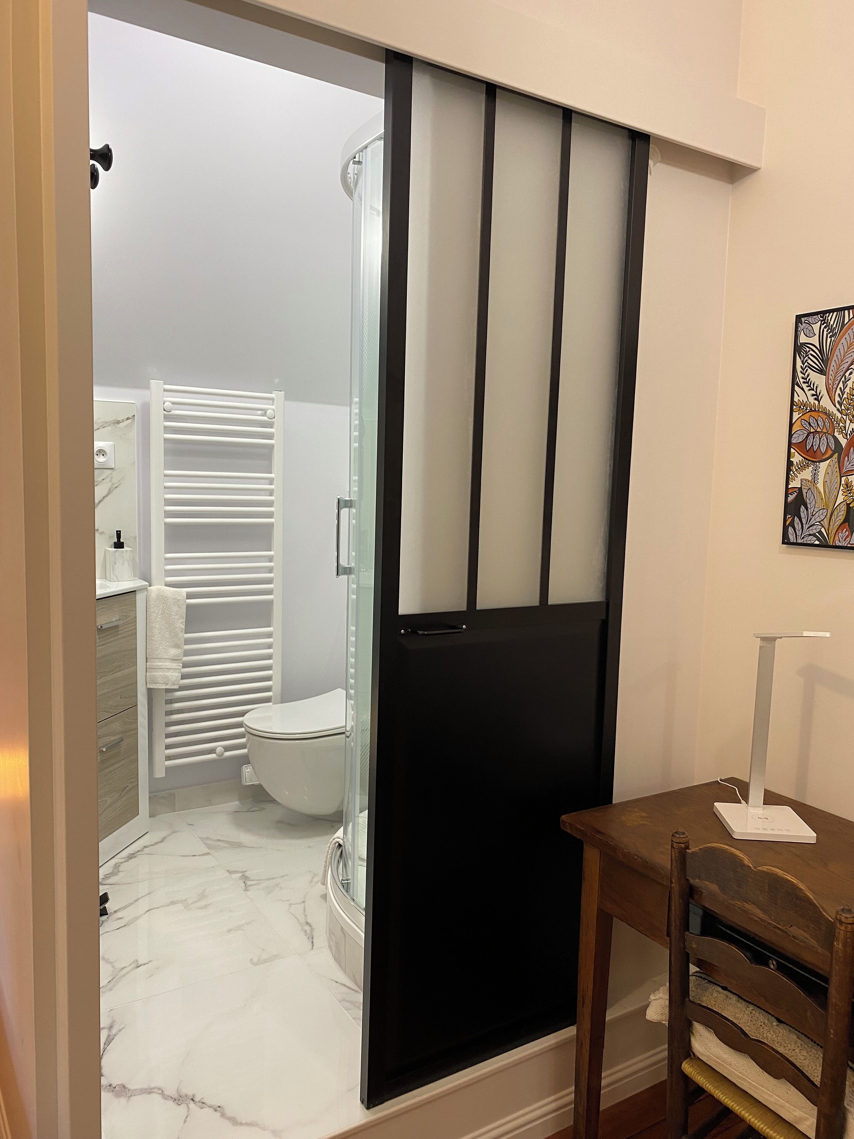 A modern bathroom with a glass shower enclosure, a white toilet, and a white towel rack.