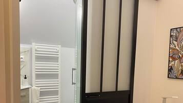A modern bathroom with a glass shower enclosure, a white toilet, and a white towel rack.
