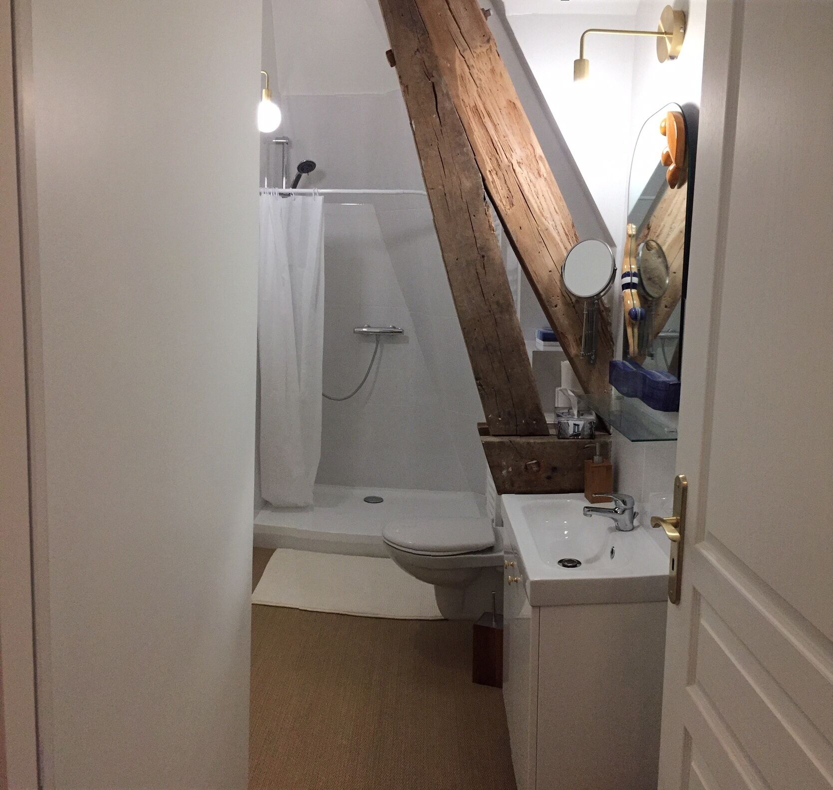A bathroom with a shower, toilet, sink, and a wooden beam structure.