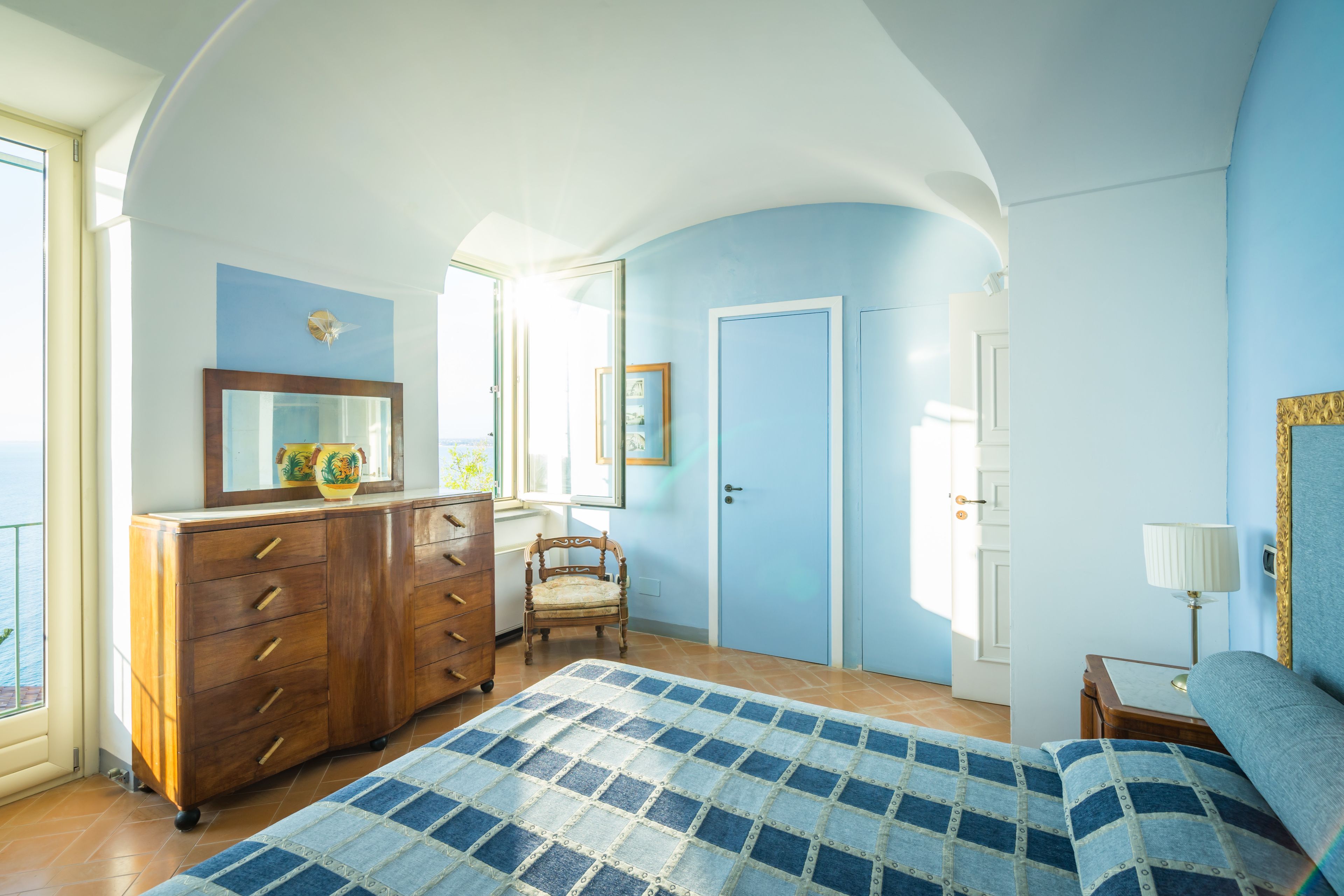 A bedroom with a bed, a dresser, a chair, and a door.