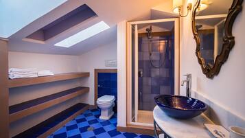 Un baño moderno con tragaluz, ducha a ras de suelo, piso azul a cuadros y un lavabo de diseño.
