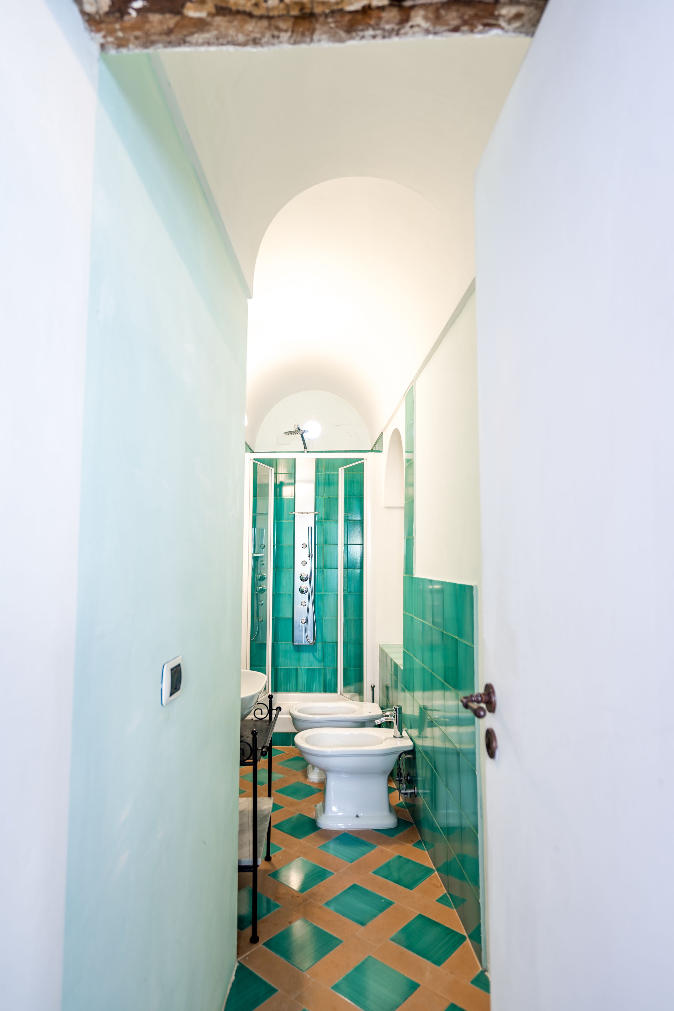 A narrow hallway leading to a bathroom with a shower, toilet, and sink.