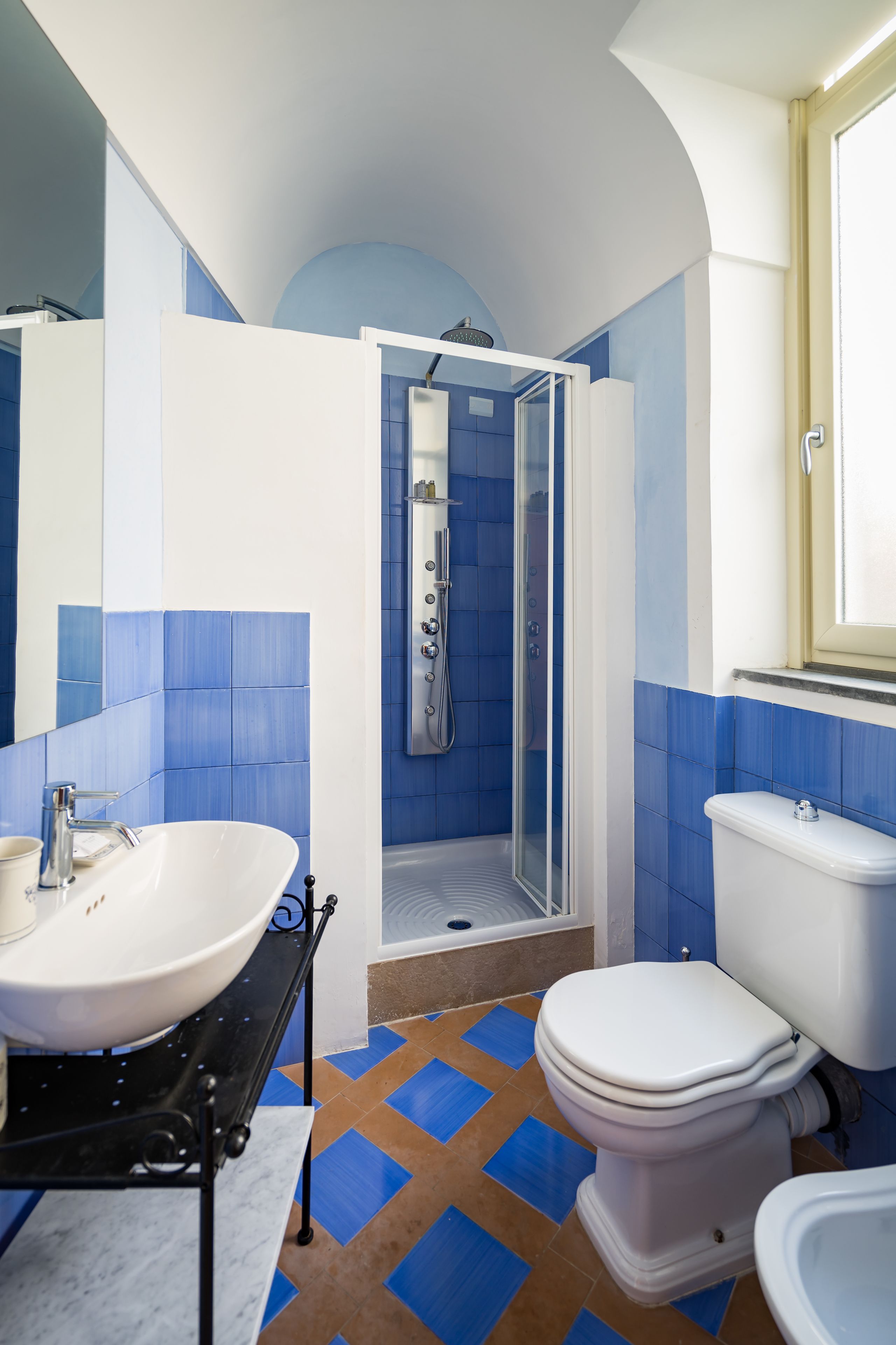Une salle de bain avec un lavabo blanc, des toilettes et une douche fermée par une paroi de verre.
