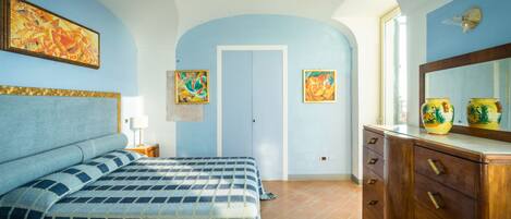 Un dormitorio con una cama, un aparador y dos cuadros en la pared.